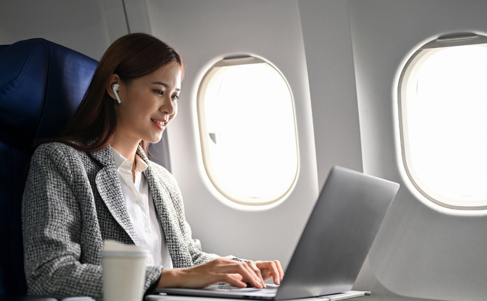 Junge Frau arbeitet am Laptop im Flugzeug